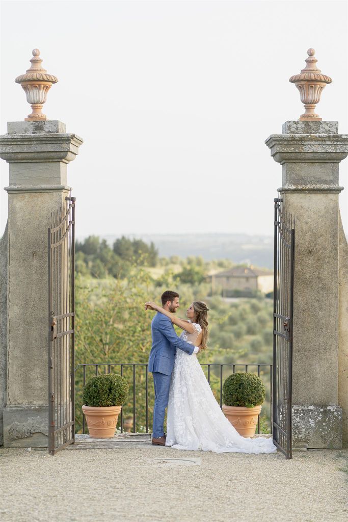 Bride and groom by the gate of the panoramic villa in the Tuscan countryside